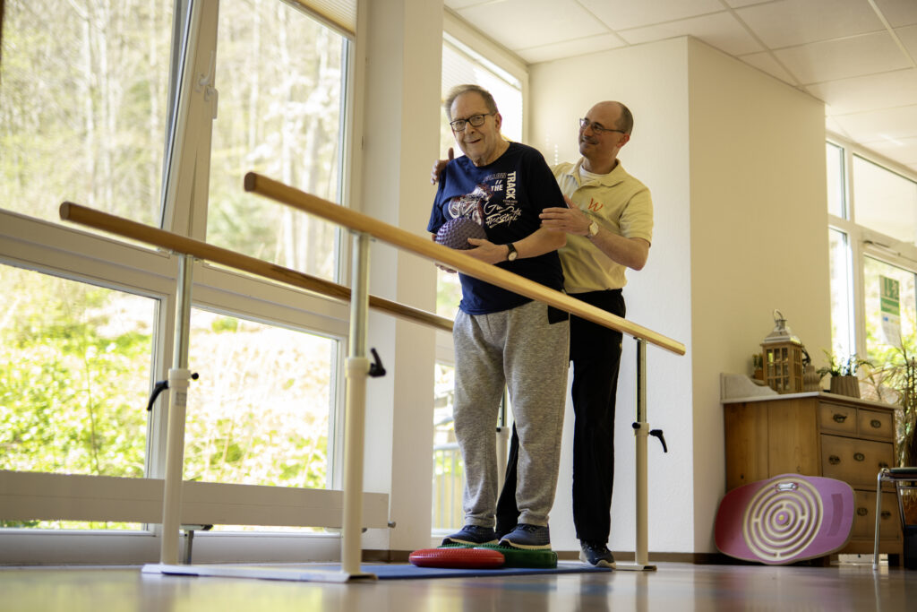 Physiotherapeut begleitet einen Patienten bei einer Gleichgewichtsübung.